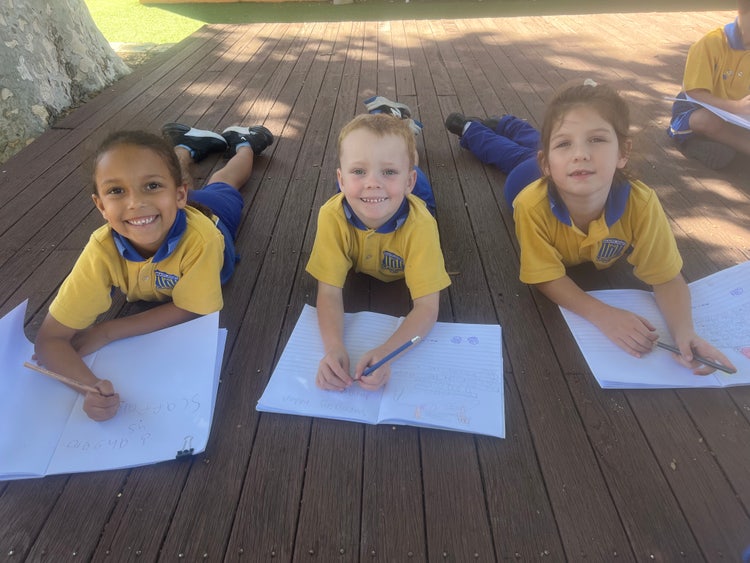 Students completing outdoor learning on one of two large outdoor deck spaces under the shade of an ancient Jacaranda tree.