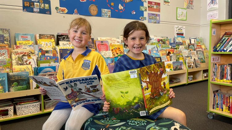 Students reading together in a well-stocked and bright library space.