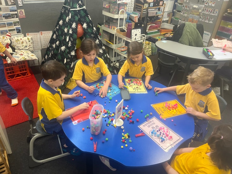 Students working in a bright and engaging classroom with hands on resources to support learning.