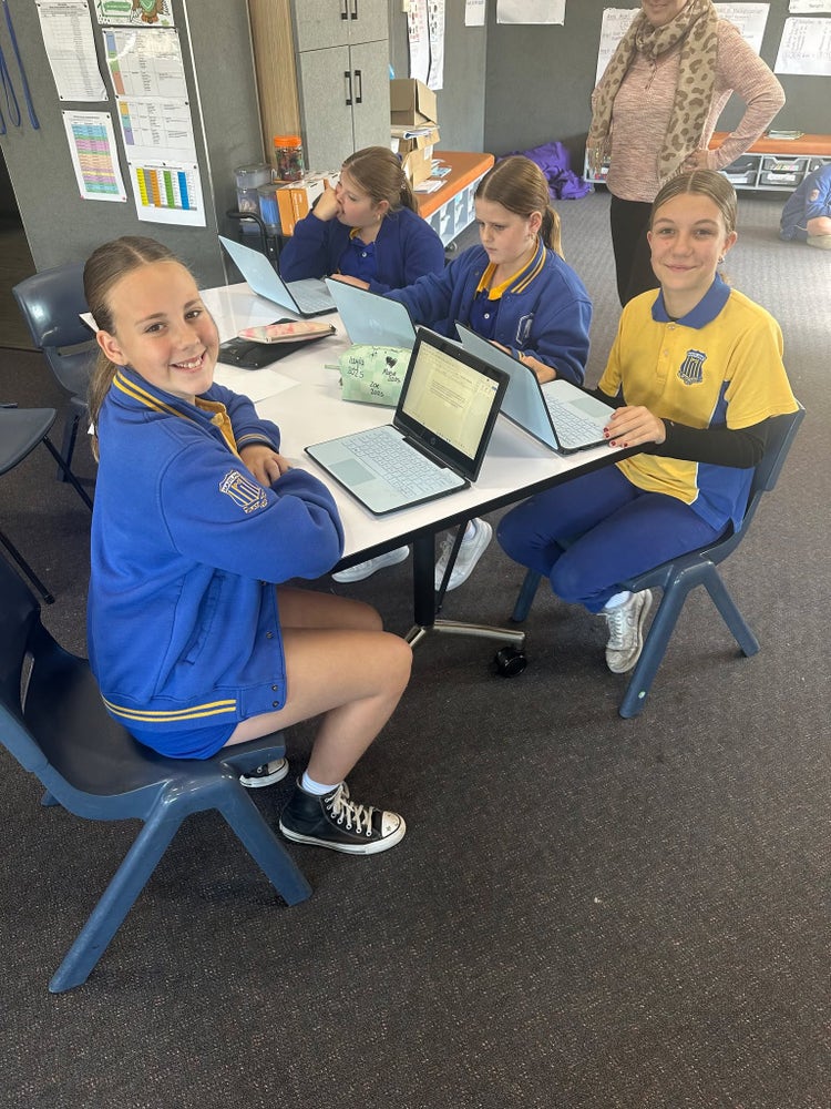 A group of Stage 3 students working in their classroom on laptops.